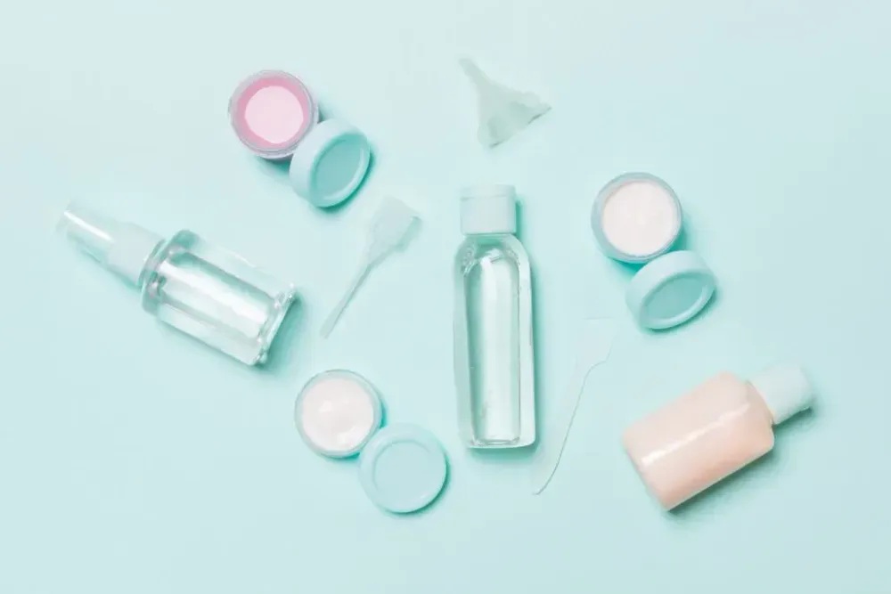 Various travel toiletry bottles laid on out a teal backdrop